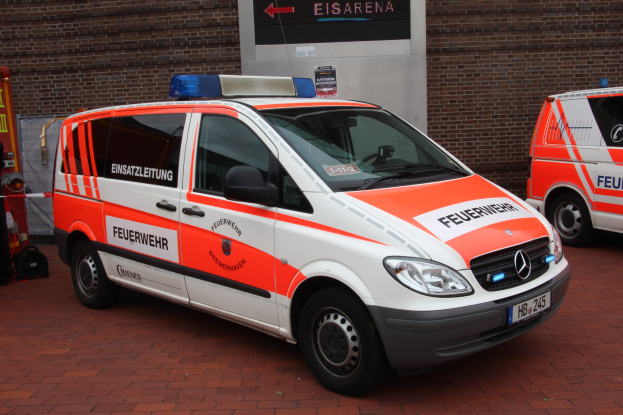 Zwei Rettungswagen nebeneinander vor einem Gebäude geparkt, mit einer Wand und einem Feuerlöscher auf der linken Seite.