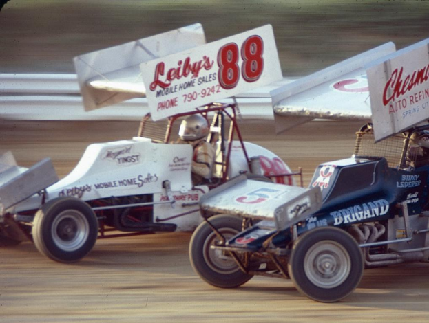 Autos auf einer Straße mit einer Sicherheitsbarriere im Hintergrund, die Szene unscharf.