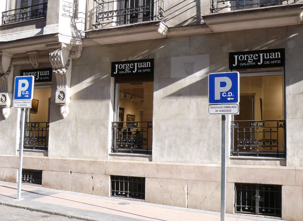 Ein mehrstöckiges Gebäude mit Fenstern, Geländern, Türen und Säulen, das Schilder an Pfosten am Gehweg und sichtbare Innenobjekte aufweist, die eine belebte städtische Umgebung suggerieren.