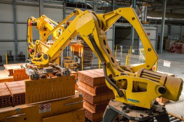 Industrielles Lagerhaus mit gestapelten Kisten, Kränen, Zaun, Pfählen und einer fernen Wand in einer Fertigungsumgebung.