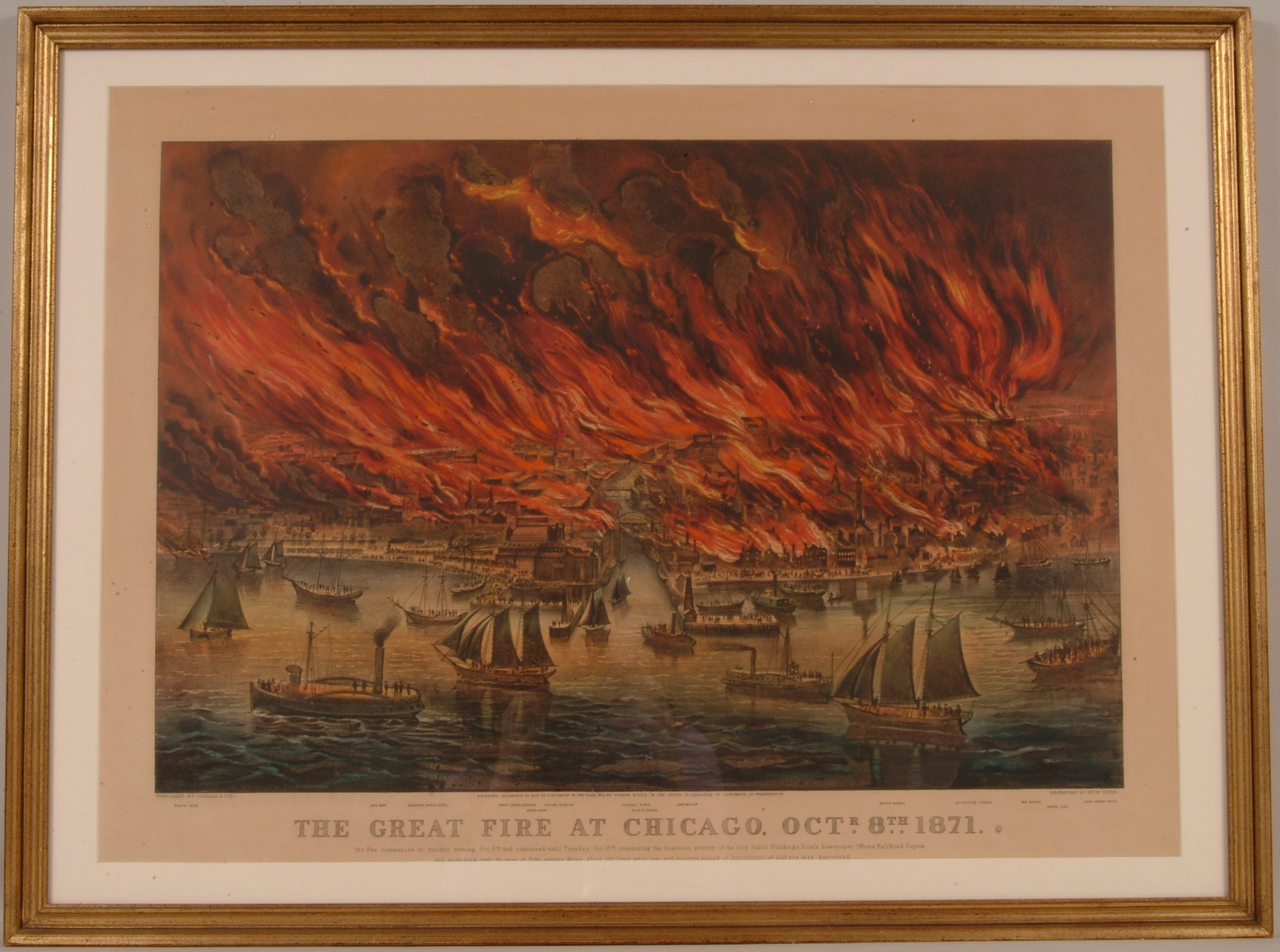 Ein Rahmenbild an einer Wand, das brennende Boote auf einem Fluss zeigt, mit dem Text "Der Große Brand von Chicago, 8. Oktober 1871" unten.