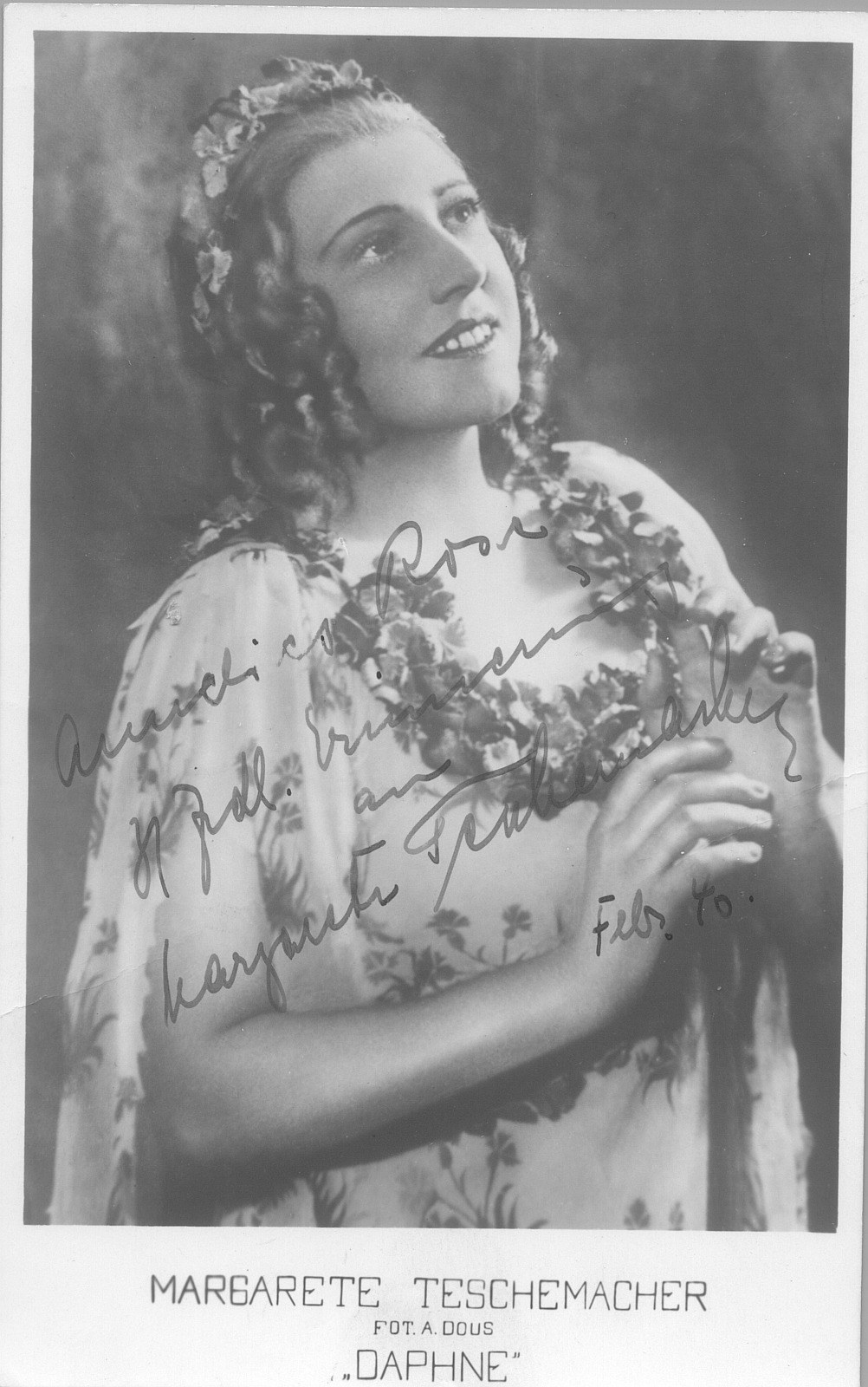 Ein Schwarz-Weiß-Foto einer Frau mit warmem Lächeln, die ein Kleid trägt und ihr Haar in einem 1940er-Jahre-Stil frisiert hat, wobei ihre leuchtenden Augen und leicht geöffneten Lippen einen sanften Ausdruck erzeugen.