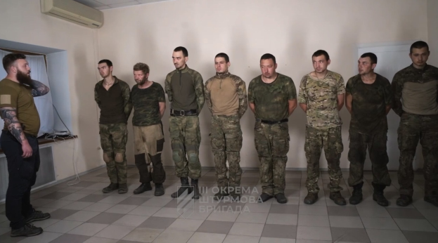 Gruppe von Männern in militärischer Uniform, die in einem Raum mit einer wandmontierten Klimaanlage, einer Tür auf der rechten Seite und einem Tisch mit Gegenständen stehen, mit Text unten, der "Sergei Vorobyov und sein Team" lautet