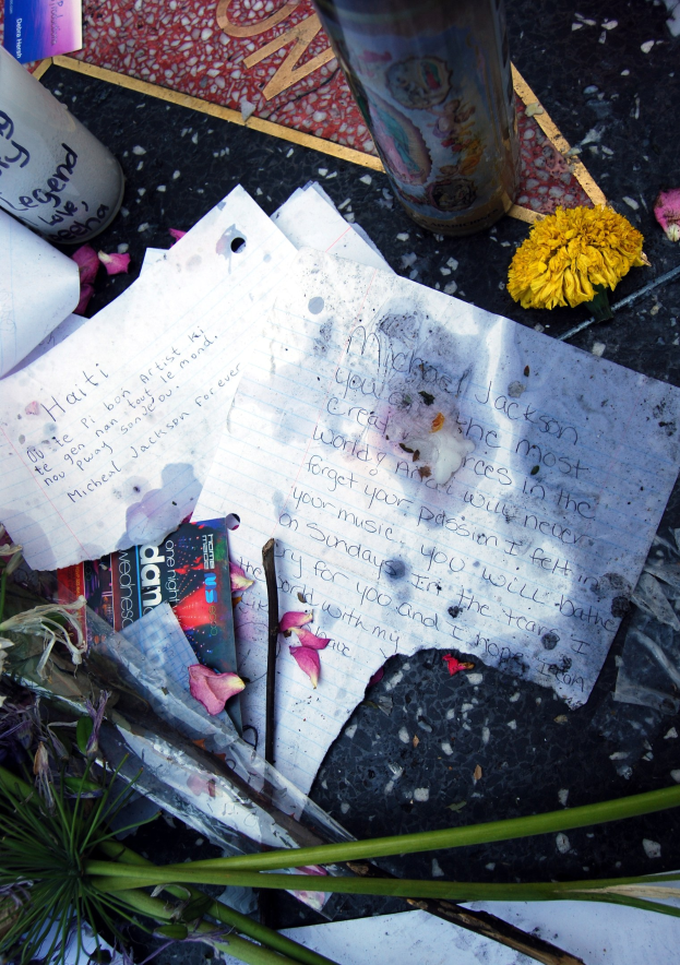 Ein Denkmal auf dem Hollywood Walk of Fame mit einem Blumenstrauß, Papieren, Büchern und einem Glas auf dem Boden.