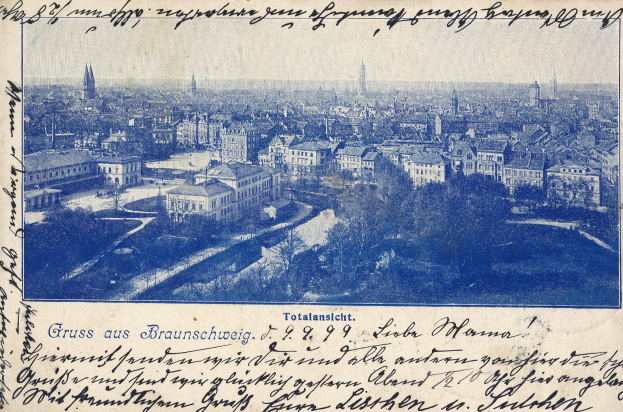 Alte Postkarte mit Stadtansicht von einem Höhenpunkt aus, mit Gebäuden, Bäumen und handgeschriebener Text.