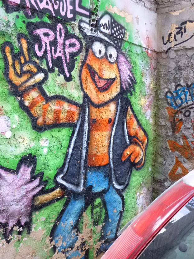 Ein rotes Auto vor einer Wand mit buntem Graffiti geparkt.
