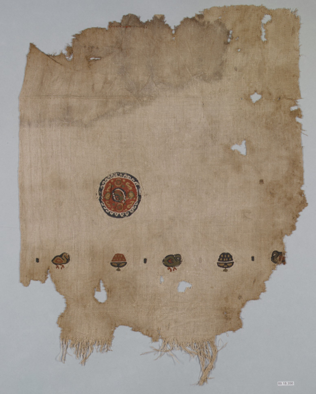 Ein Stück Stoff mit einem leuchtenden, detailreichen kreisförmigen Design, das aus verschiedenen Formen und Farben besteht, einschließlich Kreisen, Quadraten und Dreiecken, vor einem weißen Hintergrund.