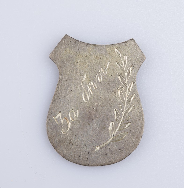 Ein silbern Abzeichen mit einem Lorbeerkranz, darauf die Inschrift "50. Hochzeitstag", auf einem weißen Hintergrund.