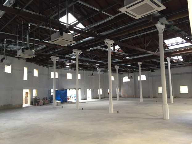 Großes Industriehallenareal mit zahlreichen Fenstern, tragenden Säulen, Deckenbeleuchtung, Klimaanlagen und einem offenen Grundriss zur Miete verfügbar.