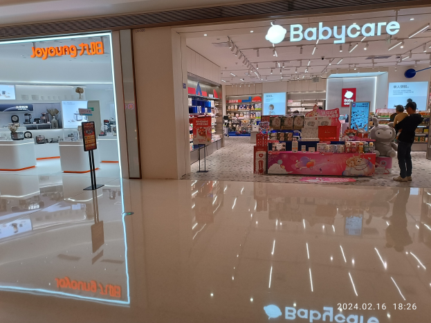 Ein Babypflegegesch├Ąft in einem Einkaufszentrum mit Menschen, Spielzeugen, Regalen, Schildern, einem Anzeigebildschirm und Deckenleuchten, das sich im Mall of Asia befindet.