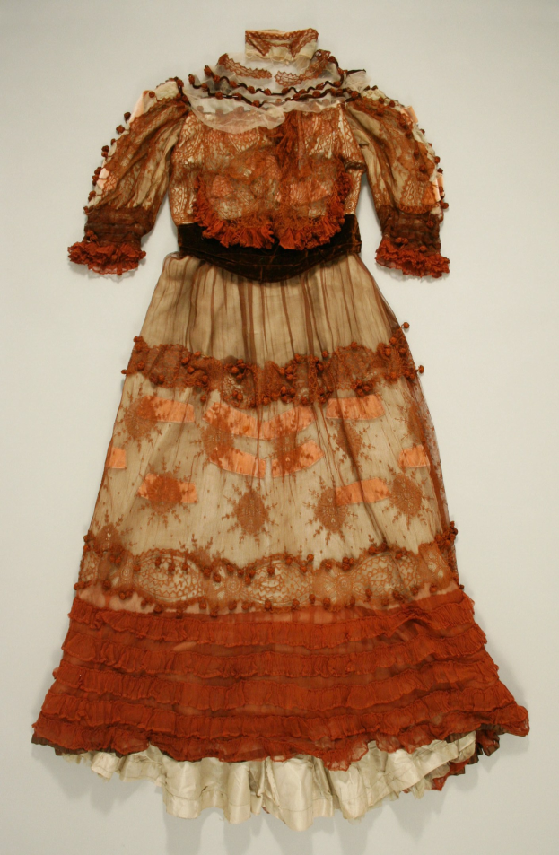 Ein leichter, luftiger Frock mit hohem Kragen, langen Ärmeln und einem bodenlangen Rock, der auf einem weißen Hintergrund in einem Museum ausgestellt wird.