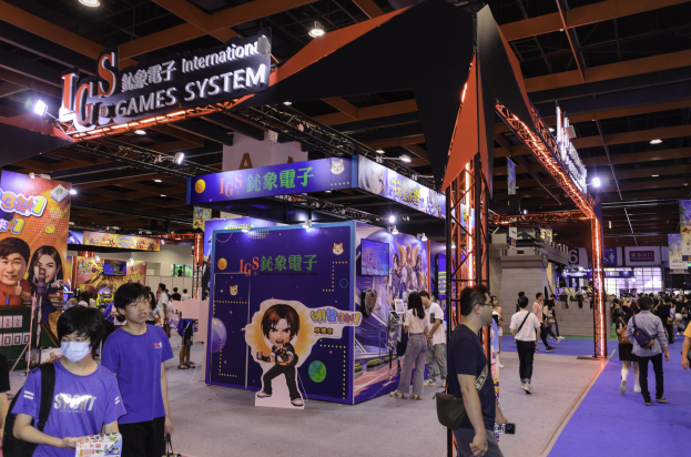 Eine Gruppe von Menschen, die durch einen Convention Hall auf einer Gaming-Expo in China gehen, einige tragen Taschen und halten Gegenstände, mit Display-Boards, Deckenbeleuchtung und einem Teppichboden.