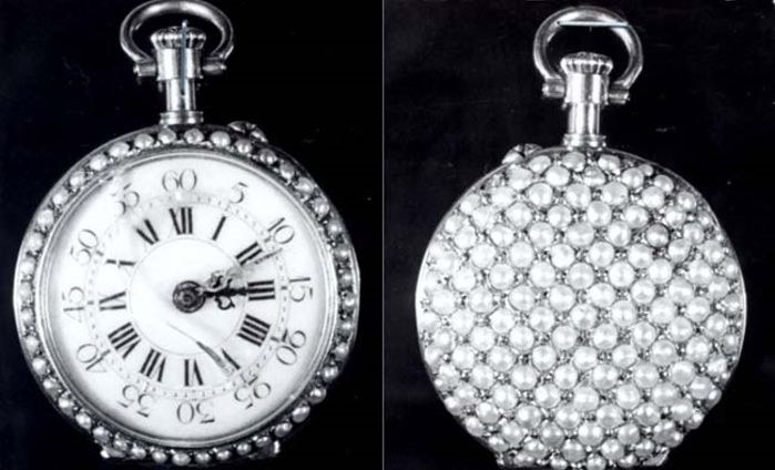 Eine silberne Taschenuhr mit Diamanten, die auf einem schwarzen Hintergrund zu sehen ist, mit einem runden Zifferblatt und römischen Ziffern.