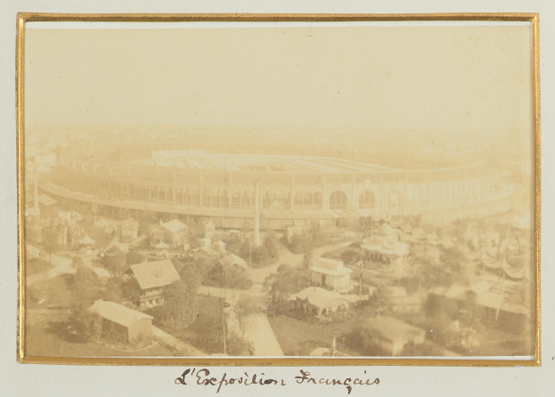 Altes Schwarz-Weiß-Foto eines Stadions in zentraler Lage in einer Stadt, umgeben von Gebäuden, Bäumen und Strommasten, mit Text am unteren Rand.