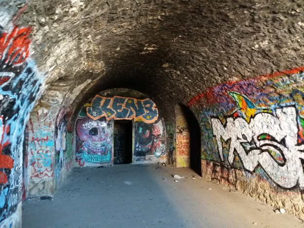 Bunte Graffiti bedecken die Wände eines Tunnels über einer Straße und schaffen eine lebendige Atmosphäre.