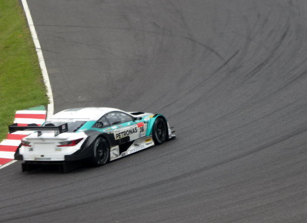 Ein silberner Mercedes-AMG GT3-Rennwagen auf einer Rennstrecke mit Text auf der Karosserie und Gras links.