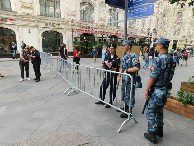 Polizeibeamte in Uniform stehen hinter Absperrungen und blicken einer Menge entgegen, einige halten Waffen, mit Gebäuden und Bäumen im Hintergrund während einer Anti-Terror-Operation in Wien, Österreich.