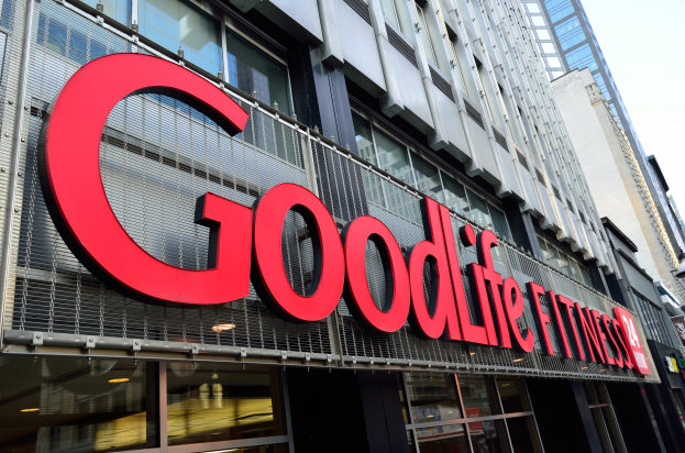 Ein Goodlife Fitness-Studio in New York City mit Glaswänden und einem Namensschild, umgeben von anderen Gebäuden unter einem sichtbaren Himmel.