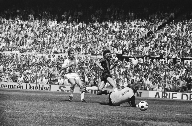 Schwarzes und weißes Foto von Männern, die Fußball auf einem Feld mit Zuschauern im Hintergrund spielen und ein Banner mit der Aufschrift "Bundesliga 1978-79 Ajax 1-1 Hannover 96."