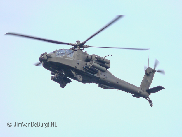 Ein militärischer Chinook-Hubschrauber fliegt mit ausgefahrenem Fahrwerk, seine Doppelrotoren drehen sich schnell gegen einen klaren Himmel.