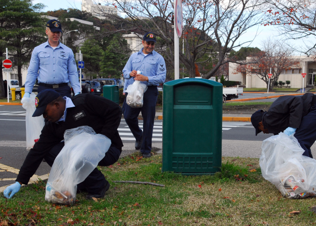 Drei Polizisten in Uniform sammeln Müll am Straßenrand