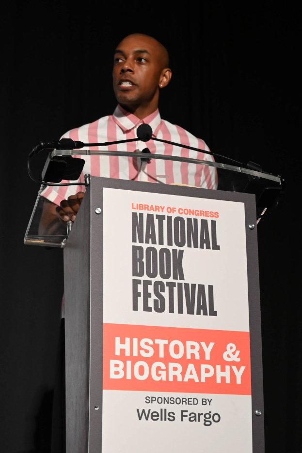 Ein Mann steht an einem Rednerpult mit einem Mikrofon und spricht bei einer Abendveranstaltung zum "National Book Festival History & Biography."