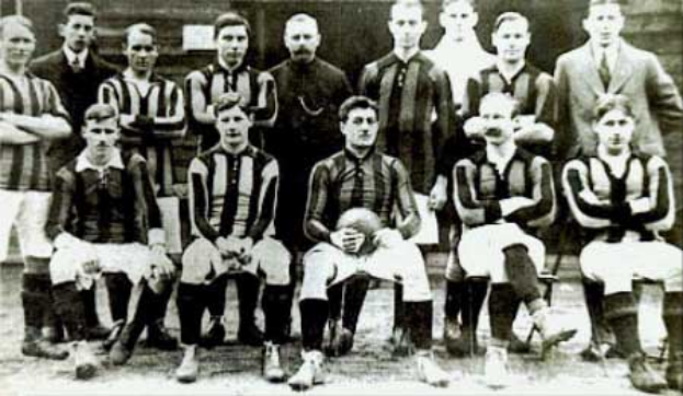 Ein Schwarz-Weiß-Foto einer Fußballmannschaft, wobei einige Spieler stehen und andere sitzen, vor einer Wand, mit dem Text "Ballymena Football Club" unten.