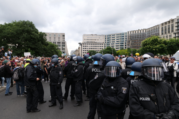 Große Gruppe von Polizeibeamten vor einer Menge während einer Demonstration in Berlin, Deutschland, mit einigen Individuen, die Kameras halten.
