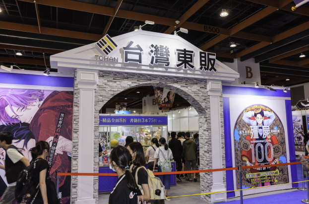 Gruppe von Menschen vor einer Spielshow-Bühne auf einer Messe mit Werbetafeln und Deckenbeleuchtung