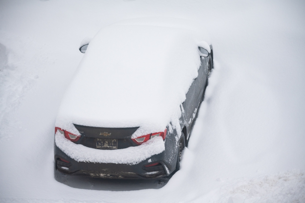 Ein schneebedecktes Auto auf einem schneebedeckten Straßenrand geparkt.