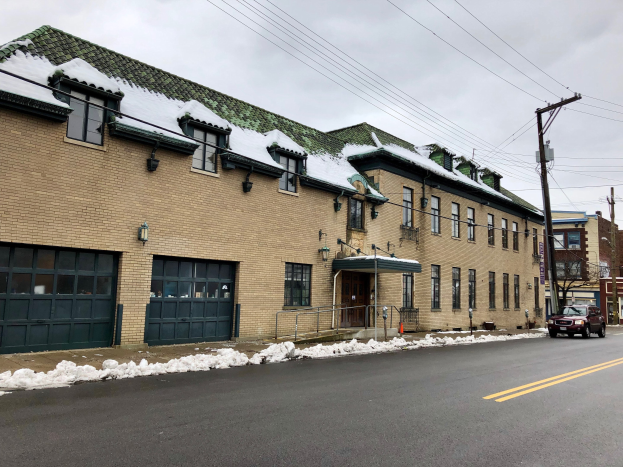 Großes Backsteingebäude mit einem grünen Dach an einer Straßenkreuzung, umgeben von Fahrzeugen, Schnee, Strommasten, Bäumen und einem bewölkten Himmel, identifiziert als die ehemalige St. Louis Fire Station.